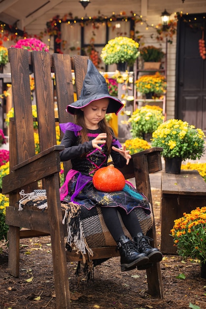 gelukkig Halloween-meisje in heksenkostuums die plezier hebben in de herfst in de buurt van het huis