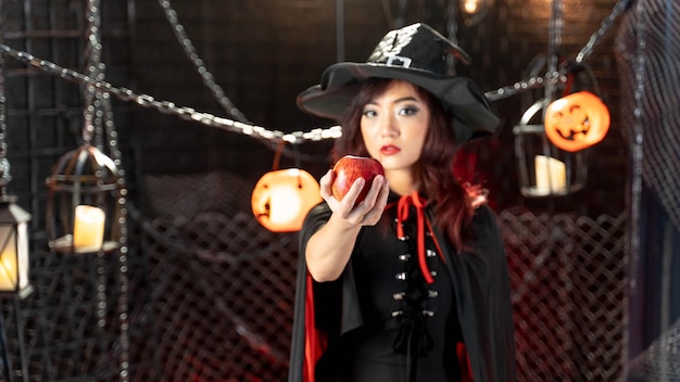 Foto gelukkig halloween mooie vrouw die heksenkostuum draagt dat appel houdt focus hand en appel