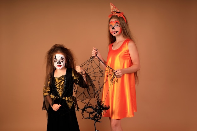 Gelukkig Halloween-portret van kinderen in kostuums op een beige muur