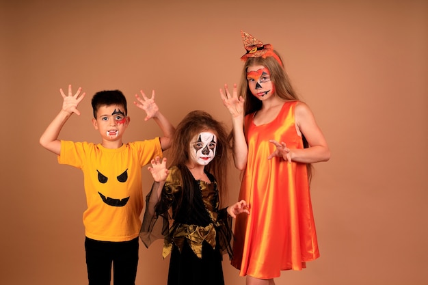 Gelukkig Halloween-portret van kinderen in kostuums op een beige muur