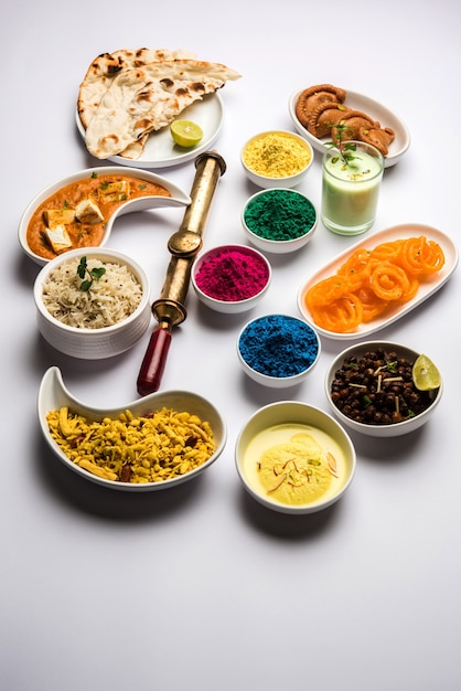 Gelukkig heilig concept met Indiaas geassorteerd lunchvoedsel zoals paneerboter masala naan jeera rijst zwarte chana bak jalebi ras malai thandai en Farsan met holi-kleuren en pichkari