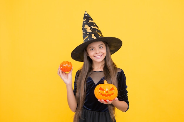 Gelukkig heks kind met pompoen jack o lantaarn draag kostuum van tovenaar op halloween-feest, halloween-attribuut.