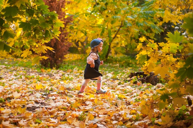 Gelukkig herfst. Een klein babymeisje speelt met vallende esdoornbladeren en lacht