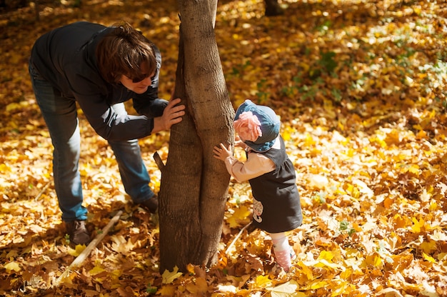 Gelukkig herfst. vader en dochter spelen verstoppertje