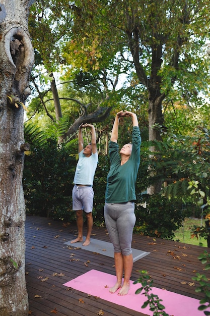 Gelukkig hoger kaukasisch paar dat yoga beoefent, die zich uitstrekt in de zonnige tuin. gezonde pensioenlevensstijl, tijd thuis doorbrengen.