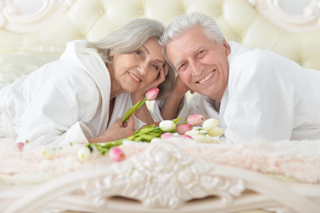 Gelukkig hoger paar met bloemen die in bed liggen