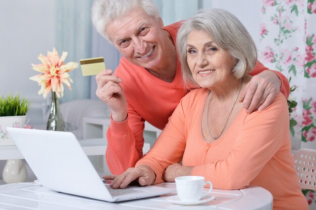 Gelukkig hoger paar met laptop en creditcard thuis