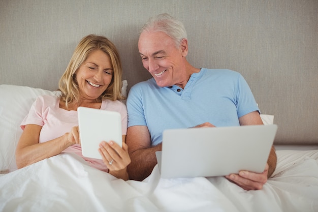 Gelukkig hoger paar op bed met laptop en digitale tablet