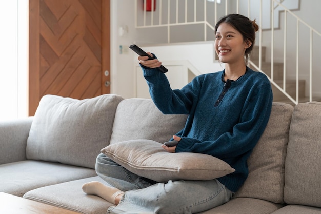 Gelukkig huis woonkamer Aziatische vrouw tv kijken ontspannen in de bank in condo appartement