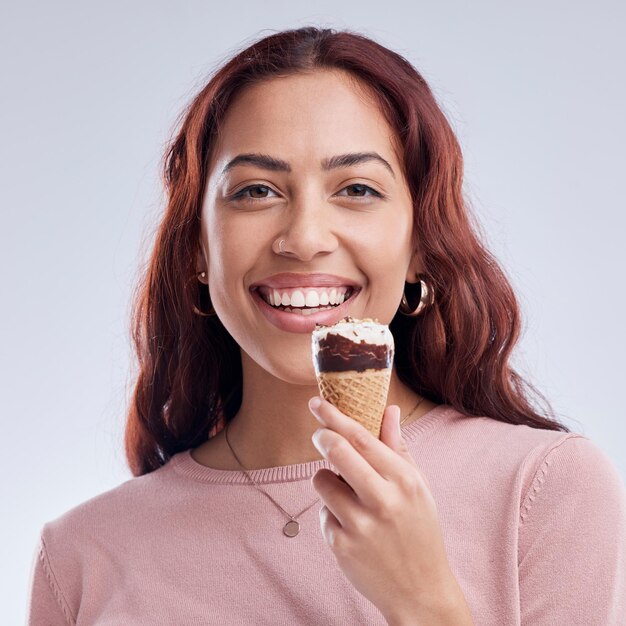 Gelukkig ijs en portret van vrouw met glimlach in studio met dessert snack en zoete lekkernijen Voedselstijl en gezicht van vrouwelijke persoon met kegel voor het eten van luxe en zomer op grijze achtergrond