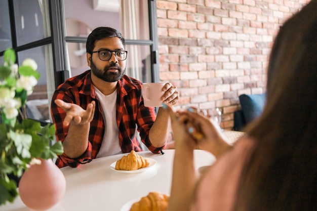 Gelukkig indisch stel ontbijten en praten samen in de keuken vriendschap dating en familie