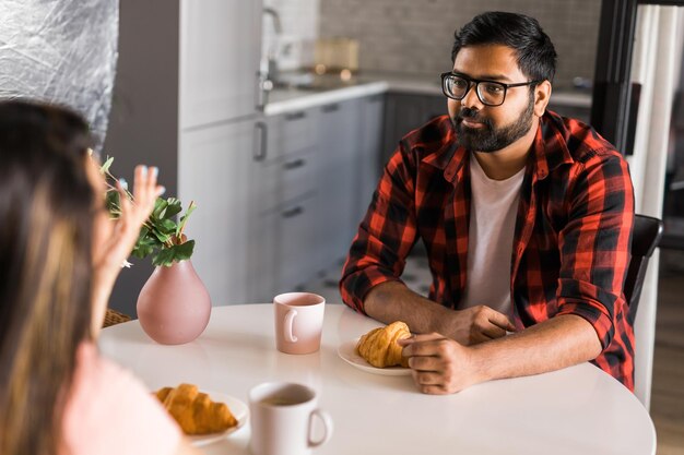 Gelukkig indisch stel ontbijten en praten samen in de keuken vriendschap dating en familie