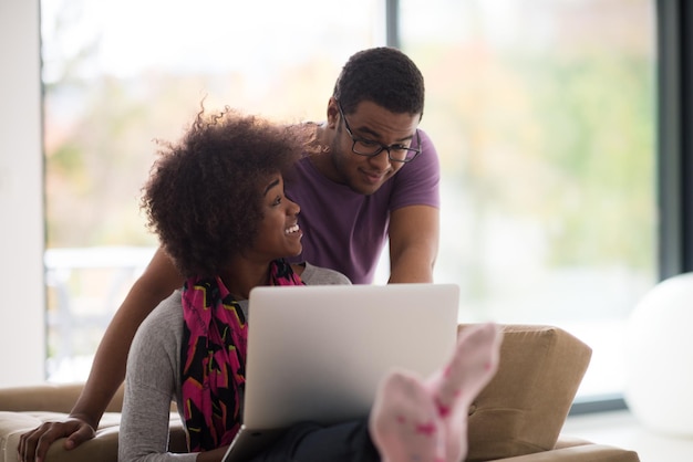 Gelukkig jong afrikaans amerikaans stel dat online winkelt via een laptop met een creditcard thuis