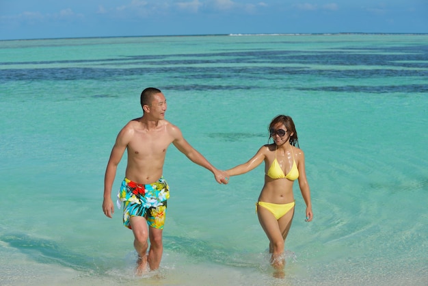 gelukkig jong Aziatisch echtpaar geniet van de zomer en hebben op een prachtig wit zandstrand