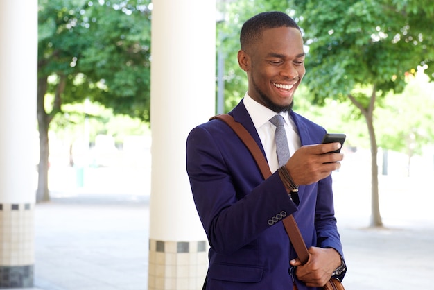 Gelukkig jong de tekstbericht van de zakenmanlezing op zijn mobiele telefoon