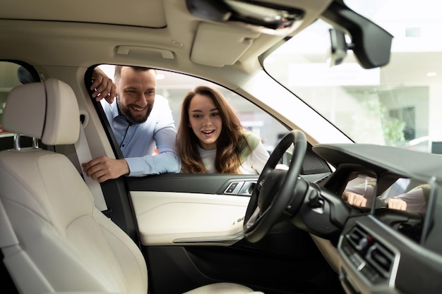 Gelukkig jong getrouwd stel kijkt naar het interieur van een nieuwe auto