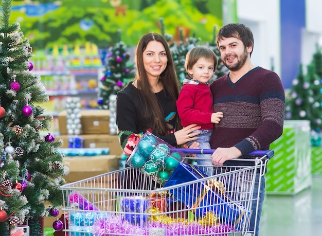 Gelukkig jong gezin in de supermarkt kiest geschenken voor het nieuwe jaar.