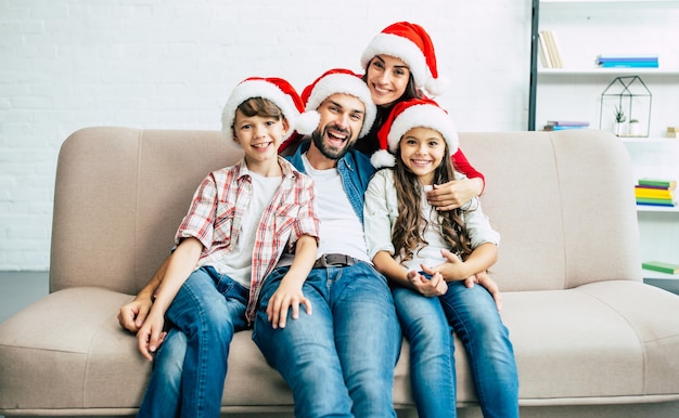 Gelukkig jong gezin in rode kerstmutsen tijd doorbrengen in de woonkamer