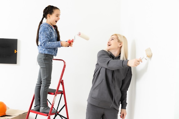 Gelukkig jong gezin met dochtertje dat de muur schildert.