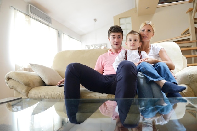 gelukkig jong gezin met kinderen in lichte moderne woonkamer veel plezier en kijken naar grote platte lcd-tv
