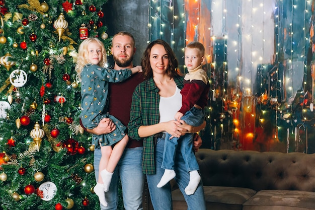 Gelukkig jong gezin met twee kinderen bij de kerstboom