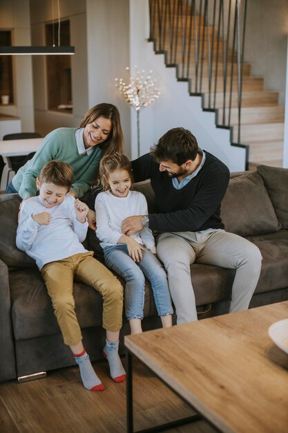 Gelukkig jong gezin met twee kinderen genieten van tijd samen op de bank in de woonkamer