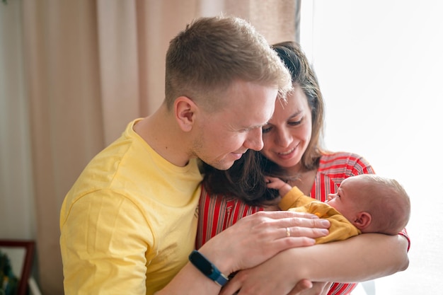 Gelukkig jong gezin met vader, moeder en pasgeboren baby in de babykamer