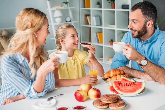 Foto gelukkig jong gezin samen ontbijten thuis