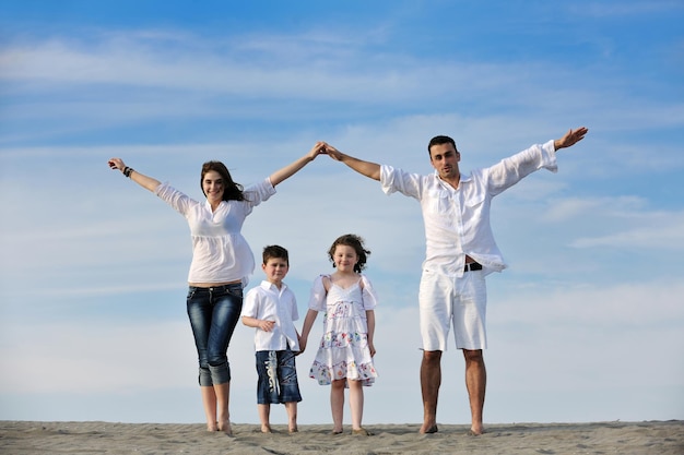 gelukkig jong gezin veel plezier op het strand en het huisbord laten zien met verbonden handen terwijl ze kinderen beschermen