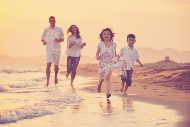 gelukkig jong gezin veel plezier op het strand rennen en springen bij zonsondergang