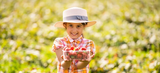 Gelukkig jong kindmeisje dat aardbeien plukt en eet op een plantage