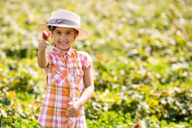 gelukkig jong kindmeisje dat aardbeien plukt en eet op een plantage