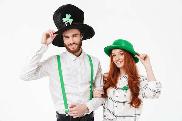 Gelukkig jong koppel gekleed in kostuums, vieren StPatrick's Day geïsoleerd over witte muur, samen plezier