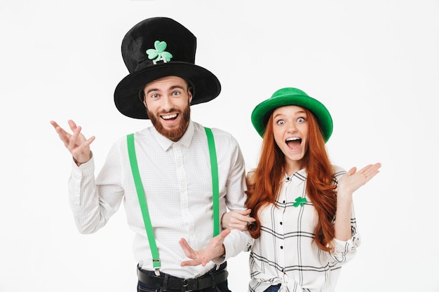 Gelukkig jong koppel gekleed in kostuums, vieren stpatrick's day geïsoleerd over witte muur, samen plezier