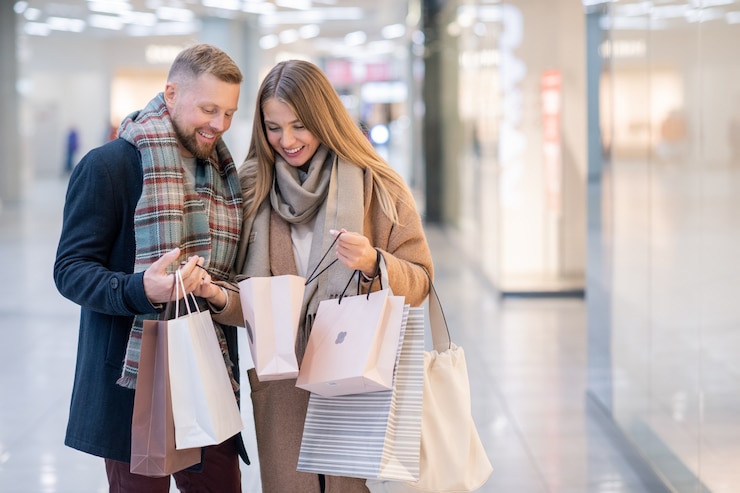 Foto gelukkig jong koppel kijken naar aankoop in een van paperbags na het winkelen in het moderne handelscentrum