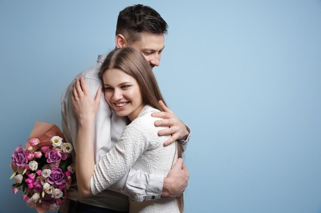 Gelukkig jong koppel met boeket bloemen op lichte achtergrond