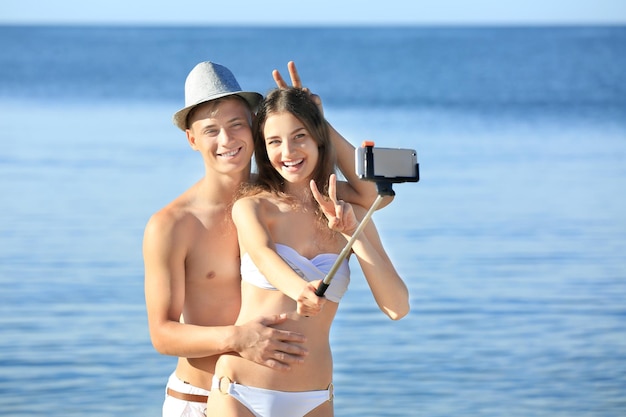 Gelukkig jong koppel selfie te nemen op zee strand in resort