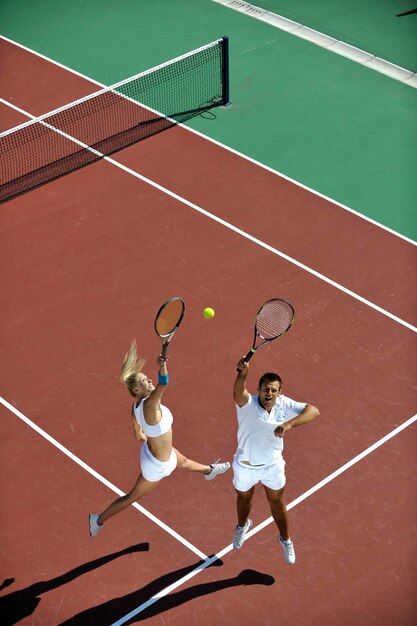 Foto gelukkig jong koppel speelt tennis buiten