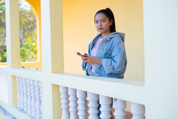 Gelukkig jong meisje dat smartphone gebruikt en op school staat