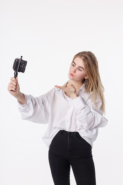 Gelukkig jong meisje die zelfportret met smartphone in bijlage aan klein driepoot maken