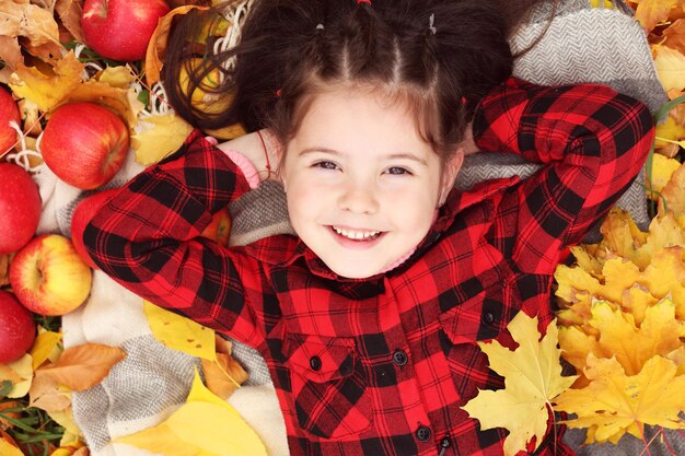 Gelukkig jong meisje liggend op plaid in herfst park