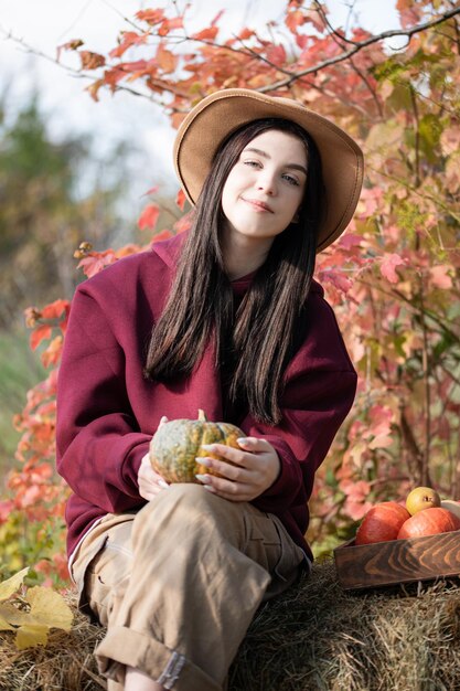 Gelukkig jong meisje met pompoen in de herfsttuin