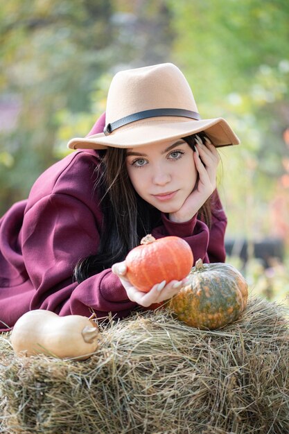 Gelukkig jong meisje met pompoen in de herfsttuin