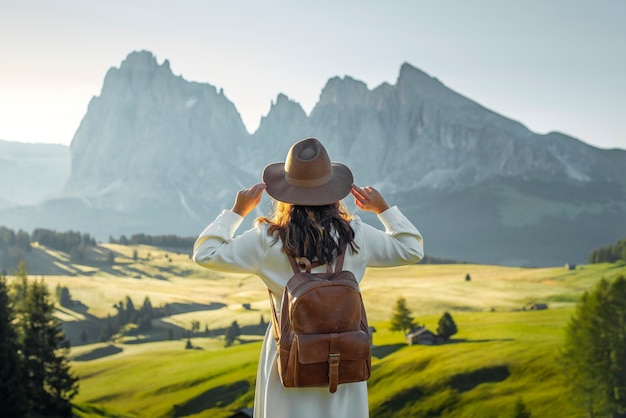 Gelukkig jong meisje met witte kledingshoed en rugzak in Alpe di Siusi Dolomieten