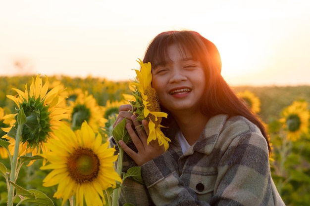 Gelukkig jong meisje op zonnebloemveld met blauwe lucht