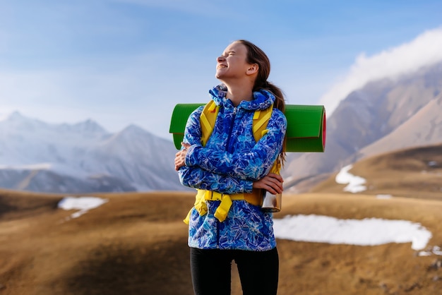 Gelukkig jong meisje reist langs de Kaukasische bergkam met een rugzak en tent, geniet van de zon en de zuivere berglucht
