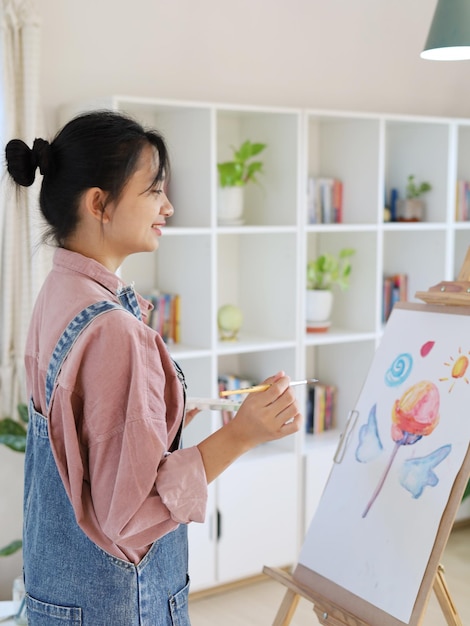 Gelukkig jong meisje tekenen met een verfpalet en een penseel bij homepainting artist
