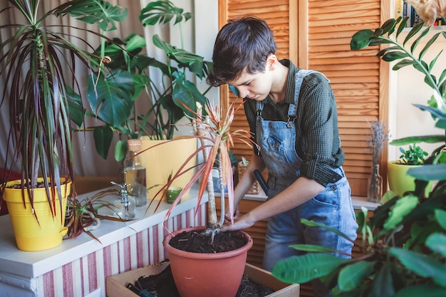 Gelukkig jong meisje verpotten huisplanten op het balkon groene omgeving in kamer tuinieren