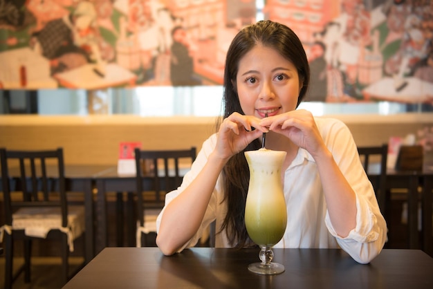 gelukkig jong meisje zittend op café winkel ogen kijken naar camera en drinken japanse iced matcha groene thee melk samen foto nemen in japan reizen middag.