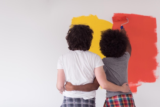 gelukkig jong multi-etnisch paar dat binnenmuur van nieuw huis schildert